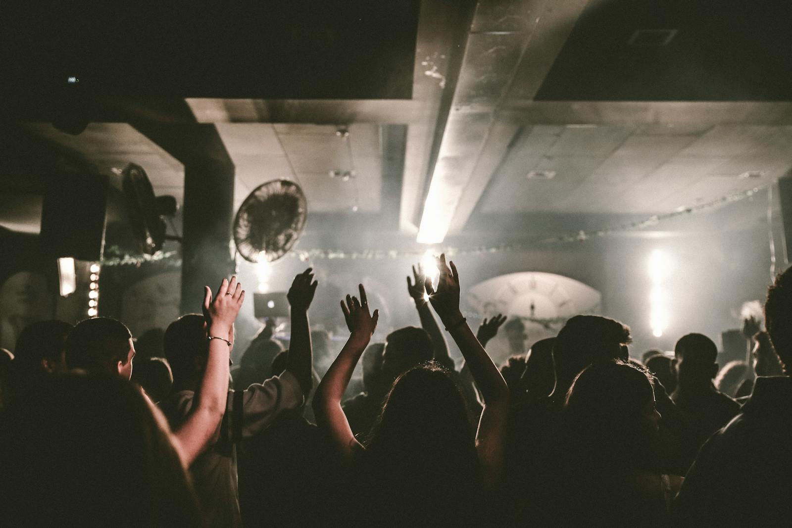 Crowd dancing with arms raised at a techno club