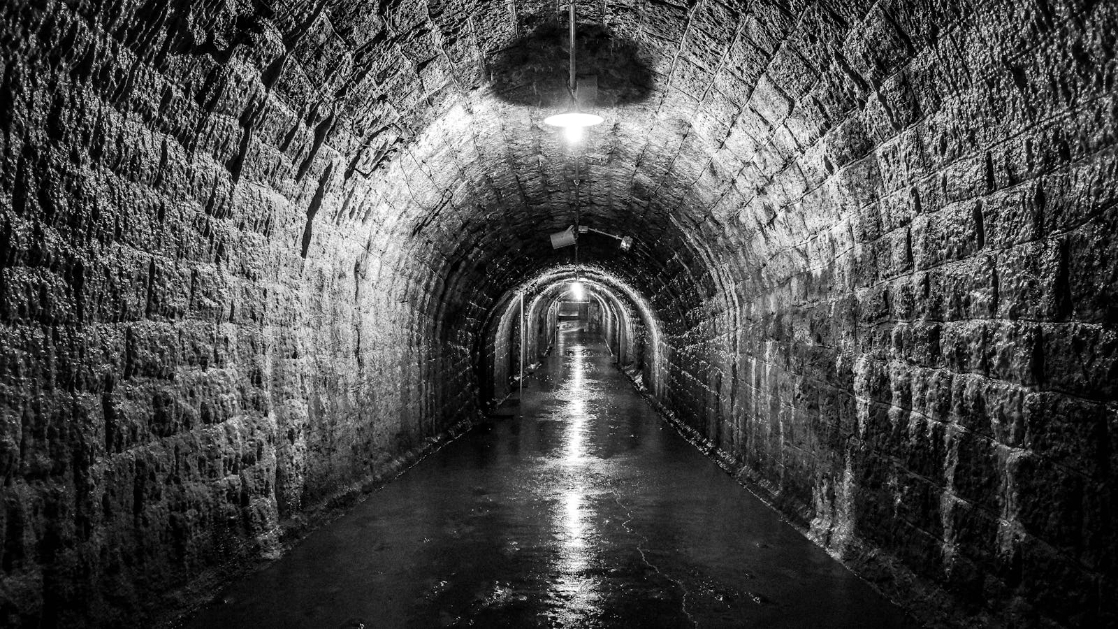 Dimly lit stone-walled underground bunker tunnel