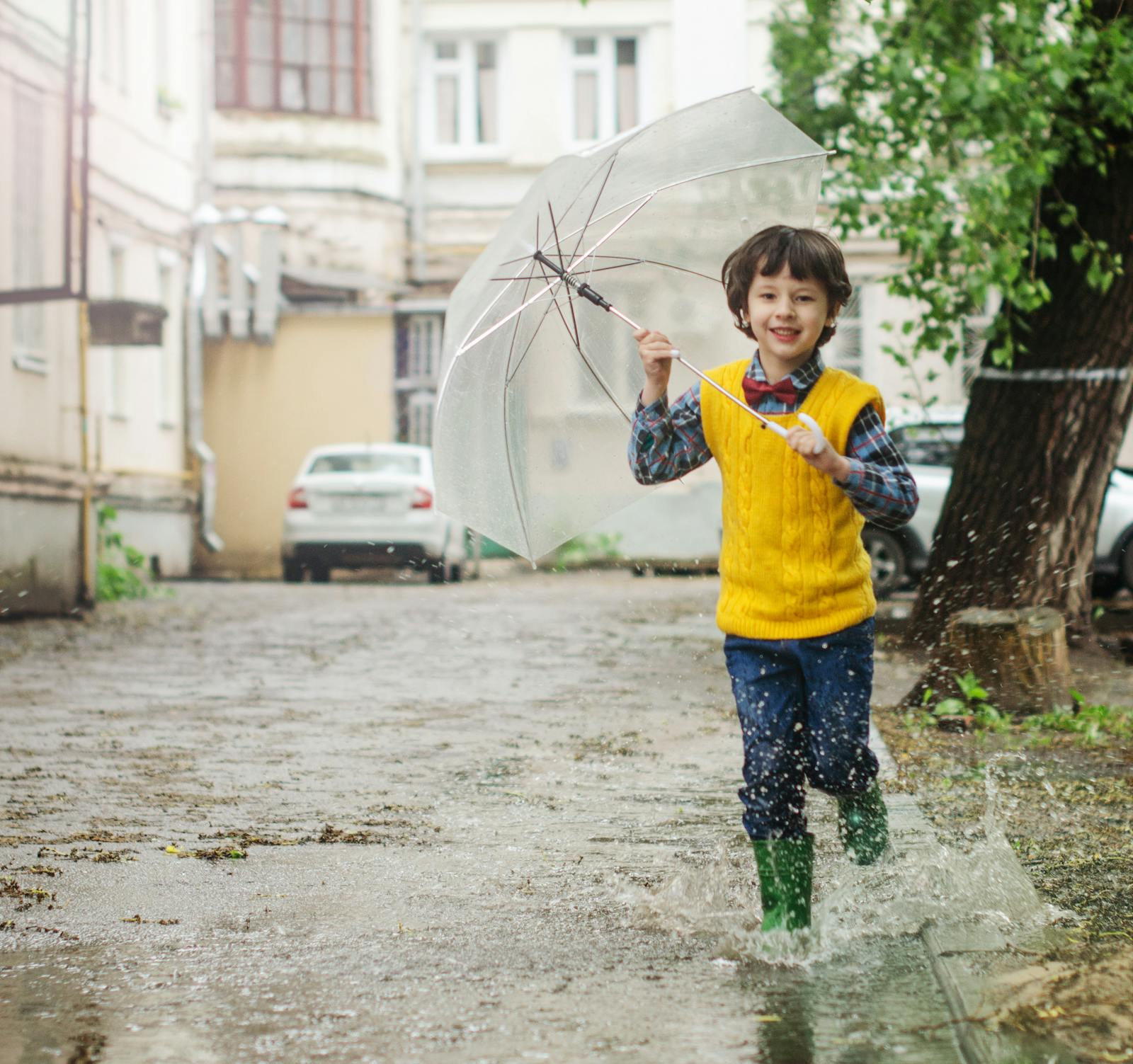 Child in yellow rain coat playing in puddles