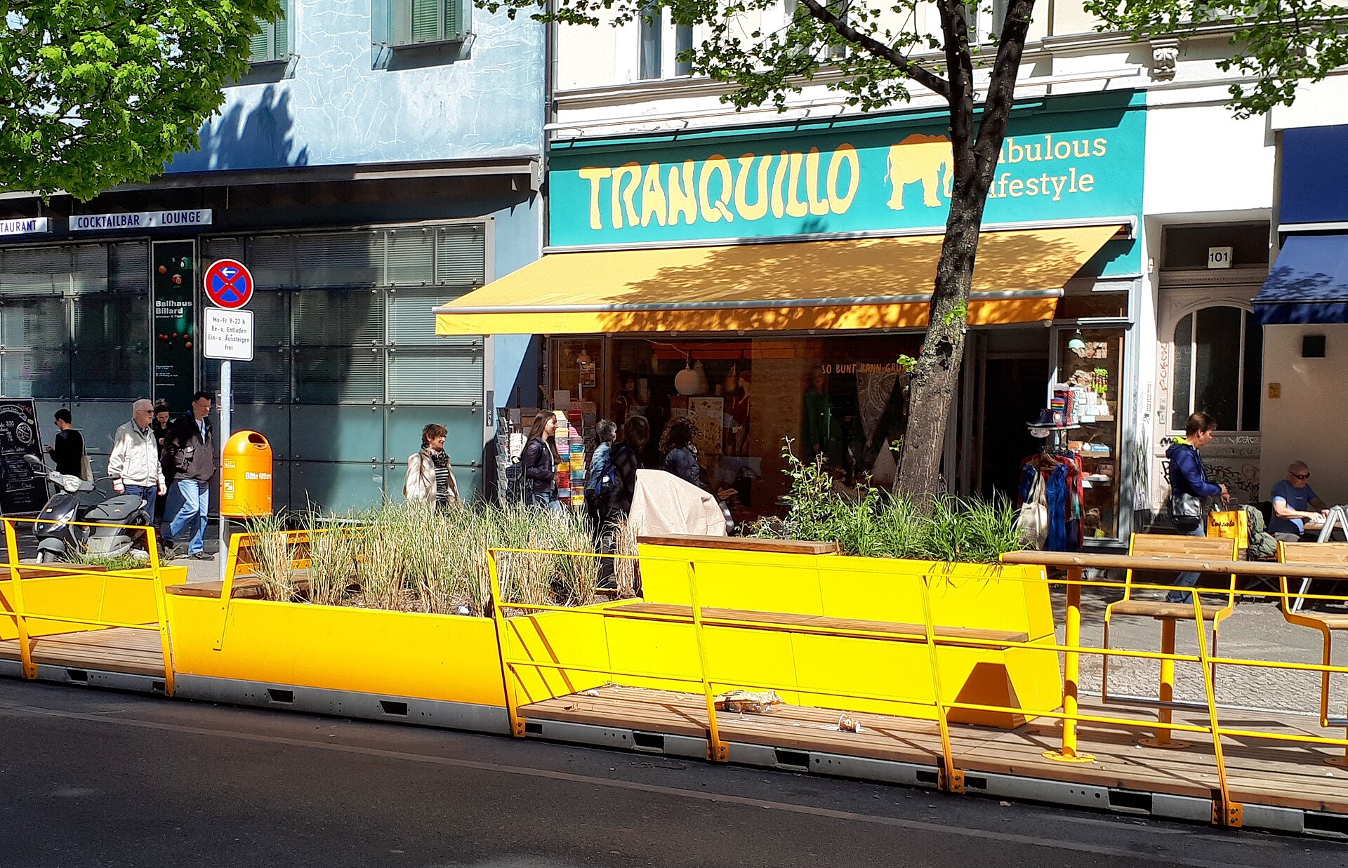 Yellow street furniture and shopfronts on Bergmannstraße in Kreuzberg on a sunny day