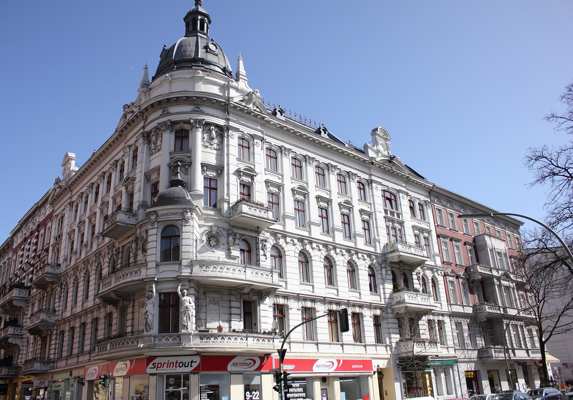 An ornate white nineteenth-century apartment building on a Berlin street corner