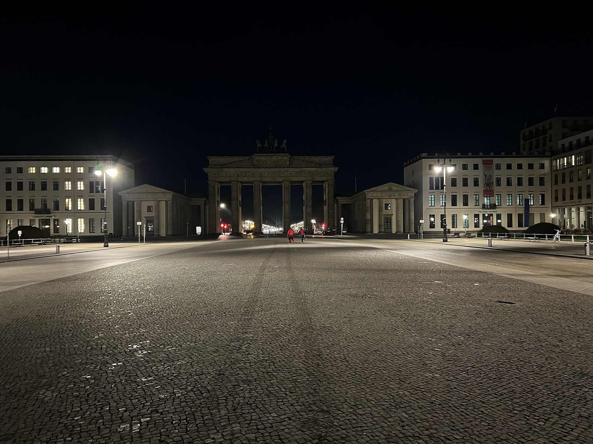 The Brandenburg Gate lit at night seen across an empty cobbled Pariser Platz