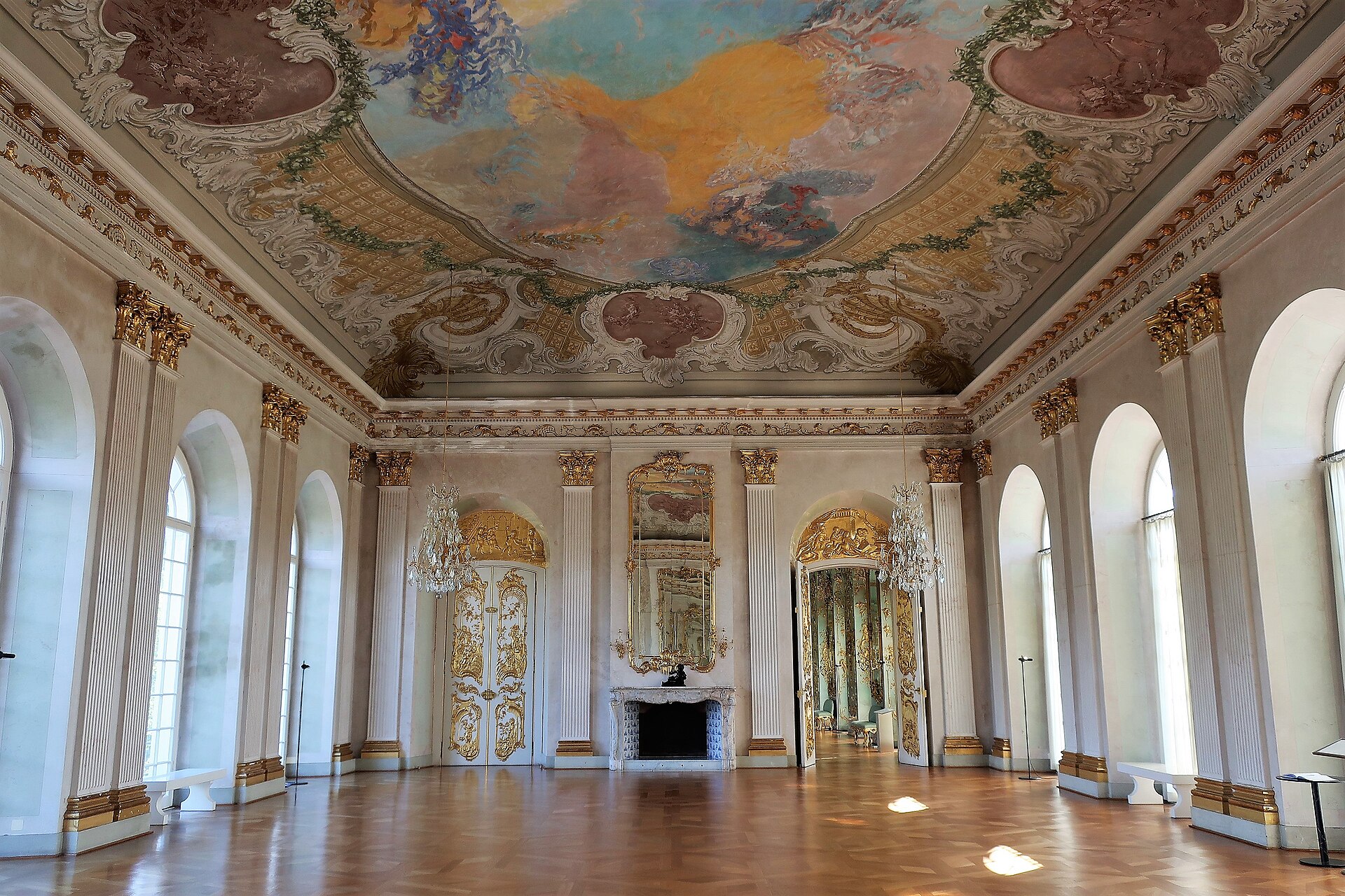 The White Hall at Charlottenburg Palace in Berlin with painted ceiling, marble columns and tall arched windows