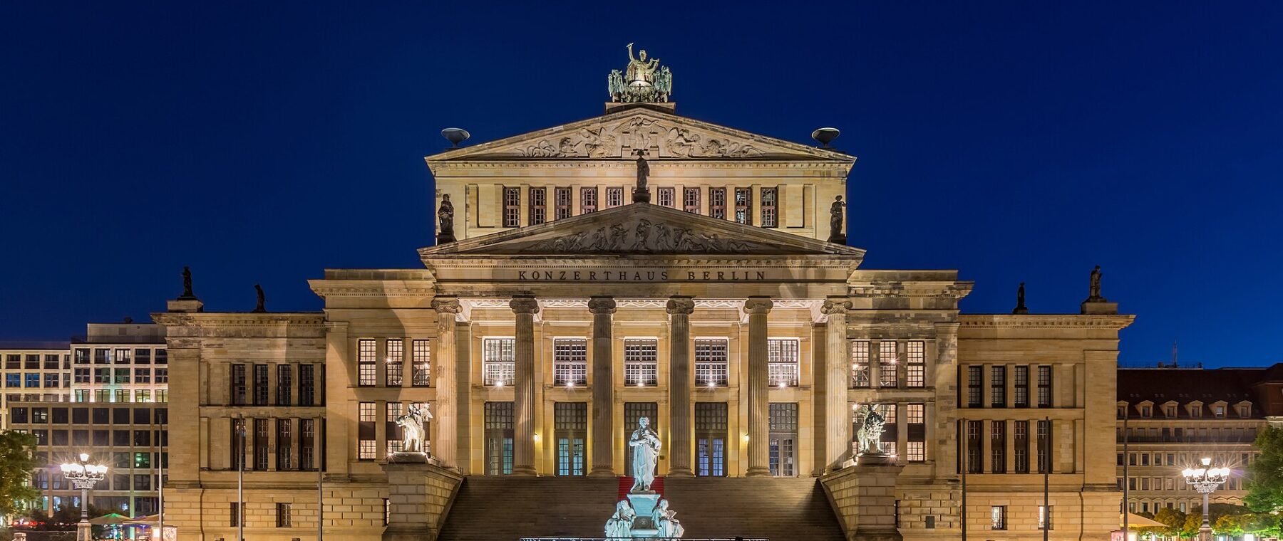 The floodlit Konzerthaus Berlin seen across the empty paving of Gendarmenmarkt at night