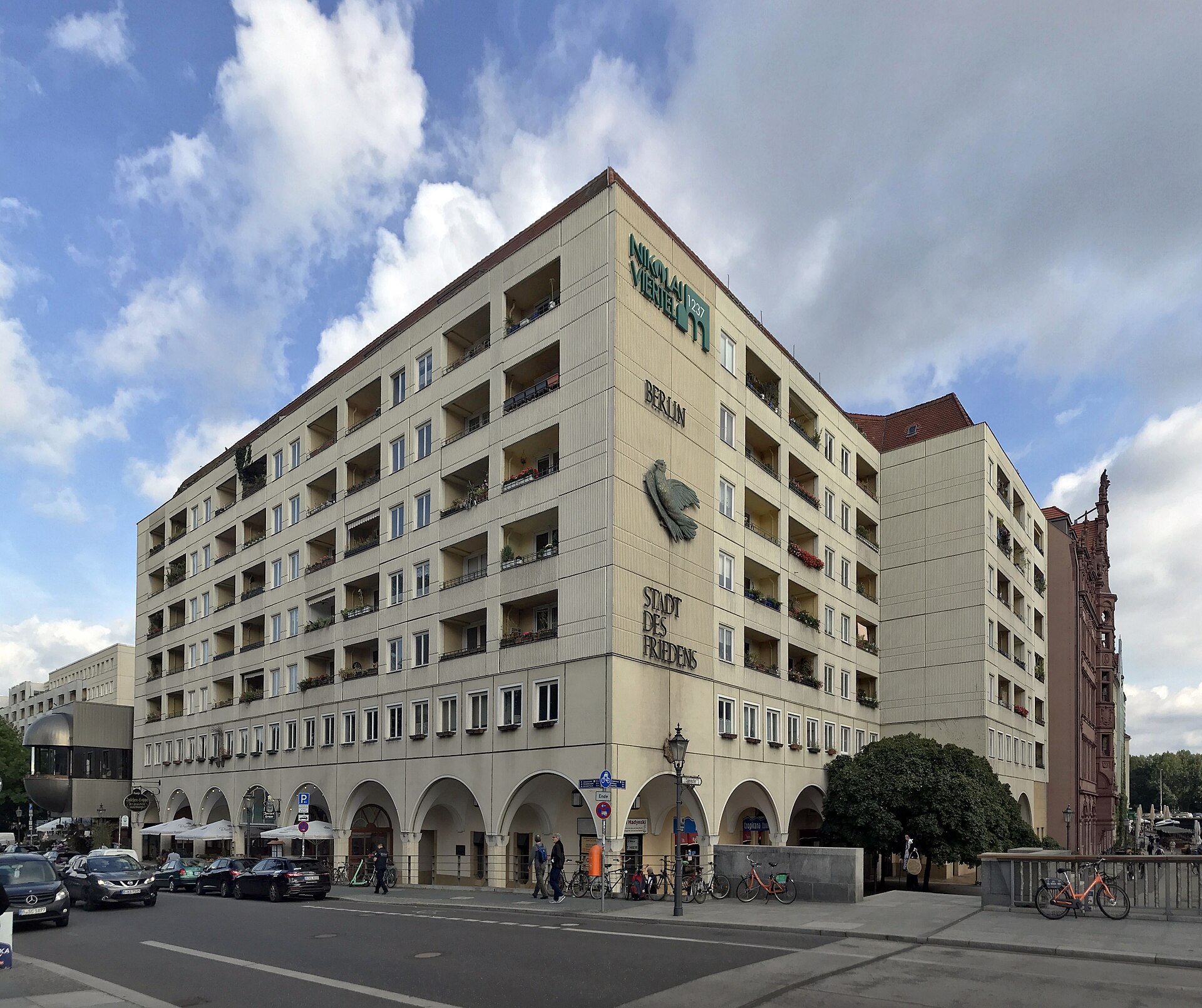A large 1980s residential block in the Nikolaiviertel carrying GDR-era lettering and a concrete peace dove