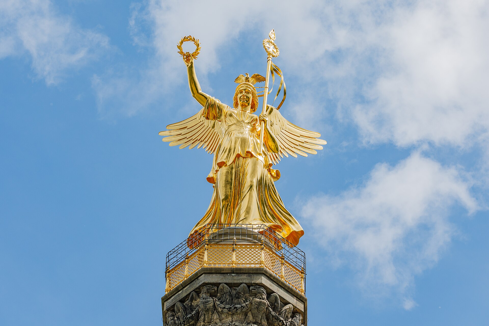 The gilded Victoria statue on top of the Siegessäule against a blue sky