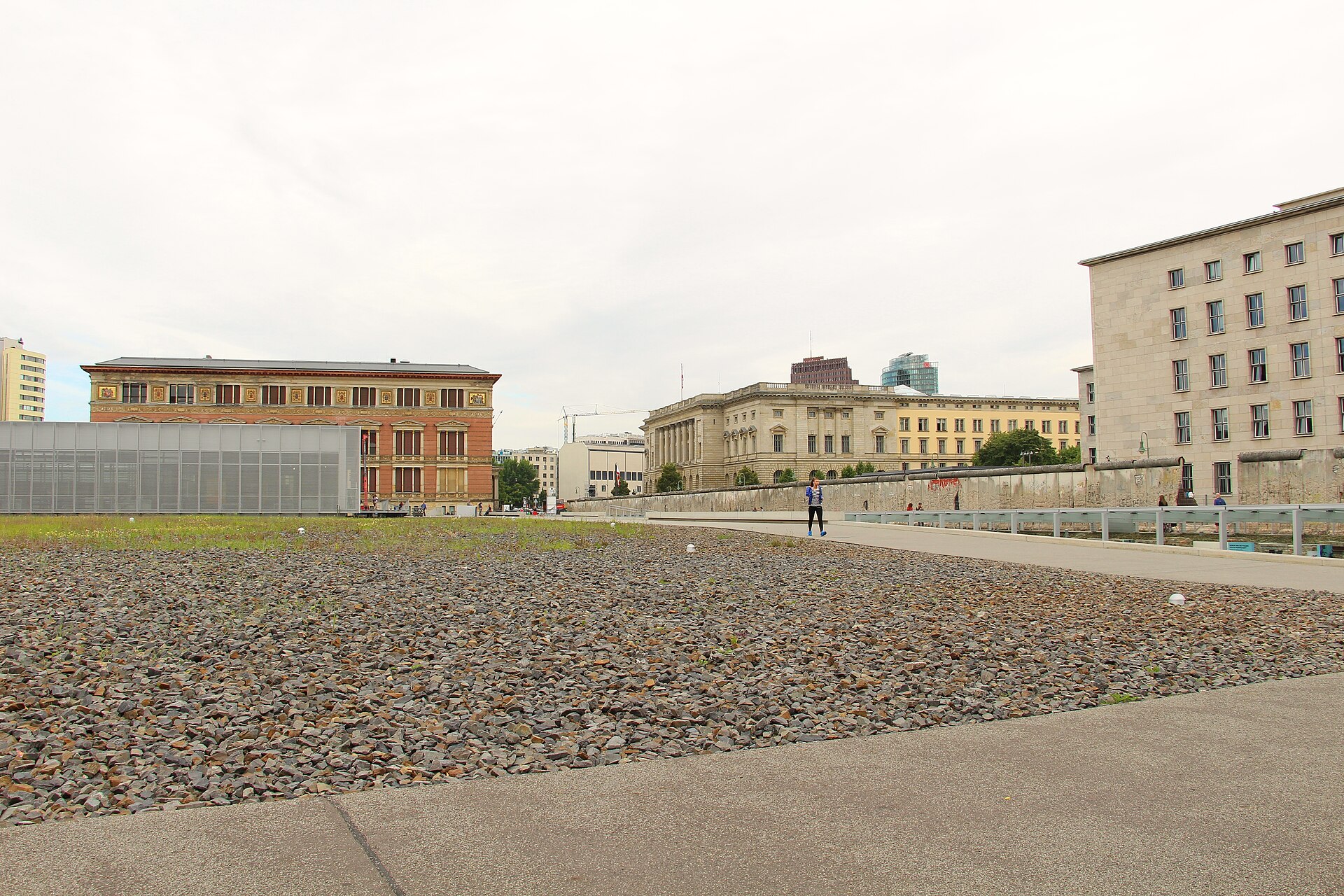 The gravel ground of the Topography of Terror site in Berlin with a preserved stretch of the Berlin Wall running along it